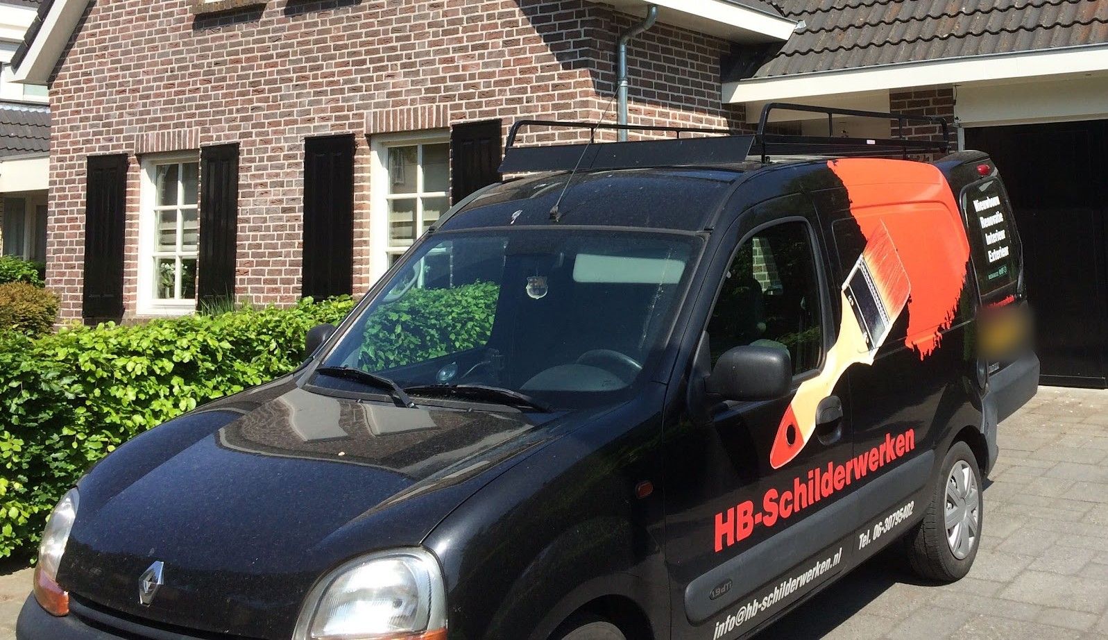 De oude zwarte bedrijfsbus van HB-Schilderwerken met rode kwast op de zijkant